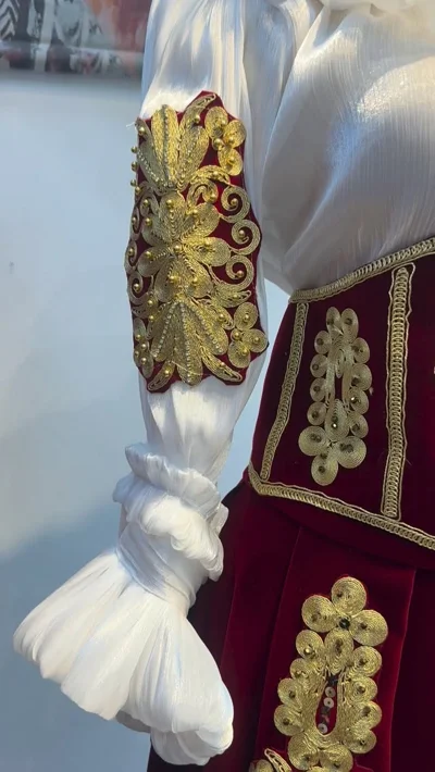 Këmishë e bardhë me jelek bordo dhe ari
