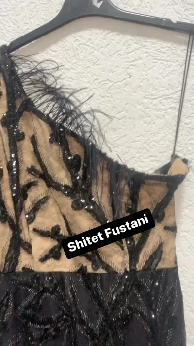Fustan i zi me një sup, pupla dhe shkëlqim