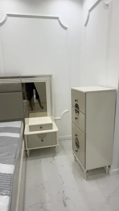 Dhomë gjumi e bardhë me komodinë dhe sirtarë