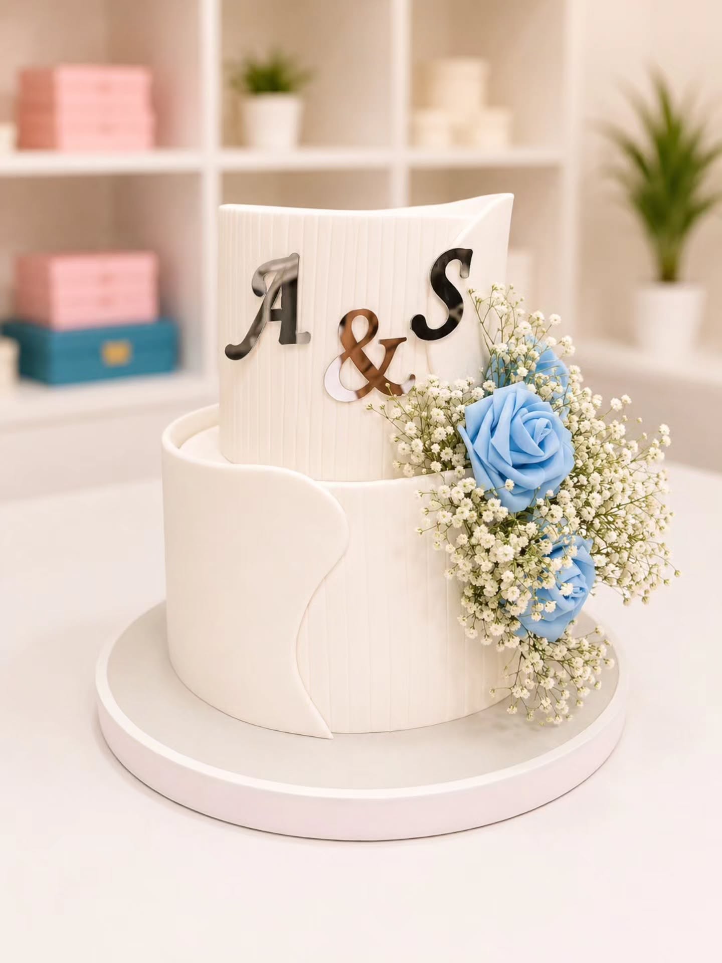 Tortë fejese dykatëshe me inicialet dhe lule blu – R-R Cakes - Torte me porosi